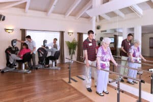 A therapist helping a resident walk in the rehab gym at Roseville Care Center
