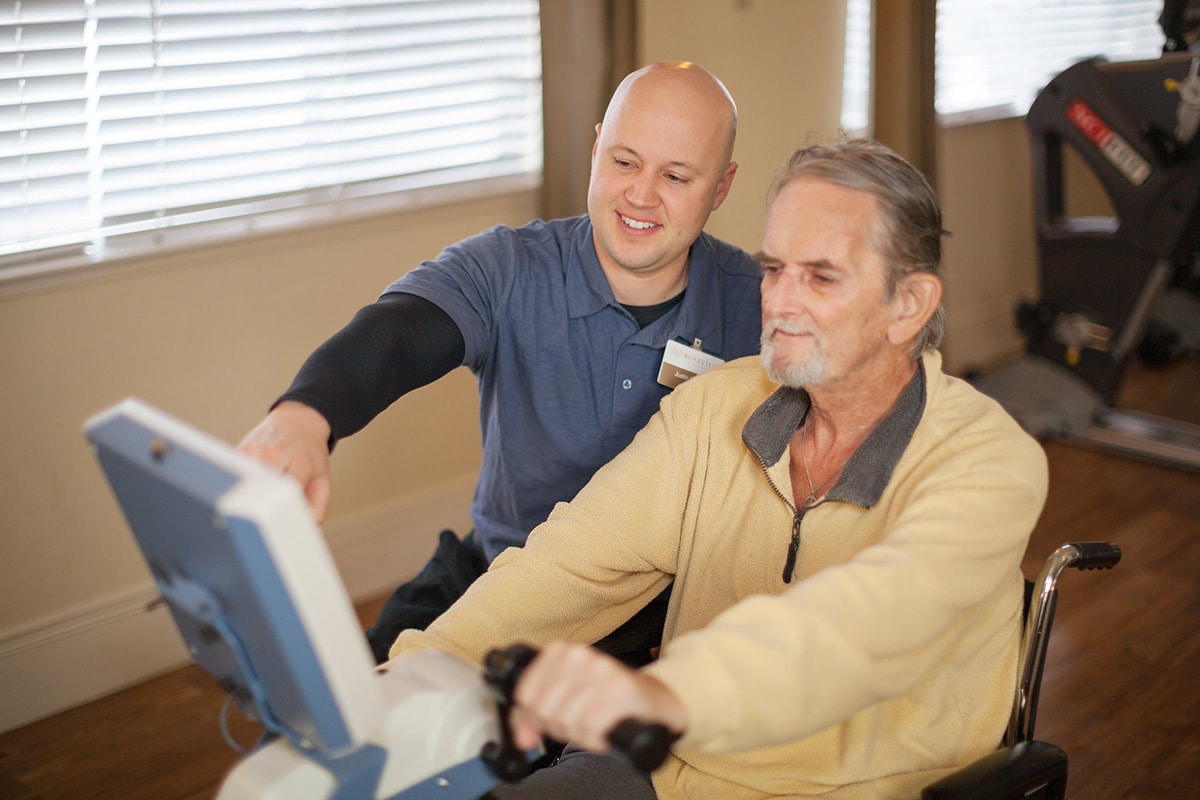 A rehab therapist helping a resident in the rehab gym at Roseville Care Center